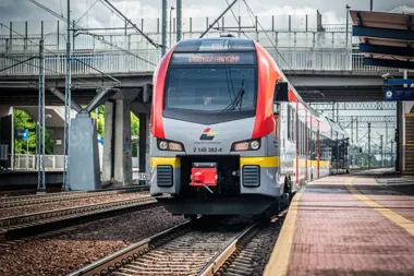 Pociąg Łódzkiej Kolei Aglomeracyjnej stoi na peronie stacji kolejowej pod wiaduktem.